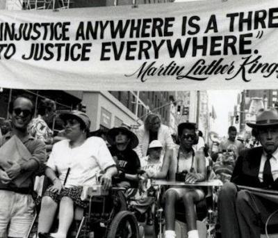 Photo of protest with banner reading "Injustice anywhere is a threat to justice everywhere" - Martin Luther King, jr.